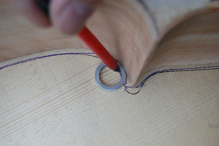 Using a slice of aluminum pipe and a ball-point pen to trace the shape of the cello front plate from the garland.